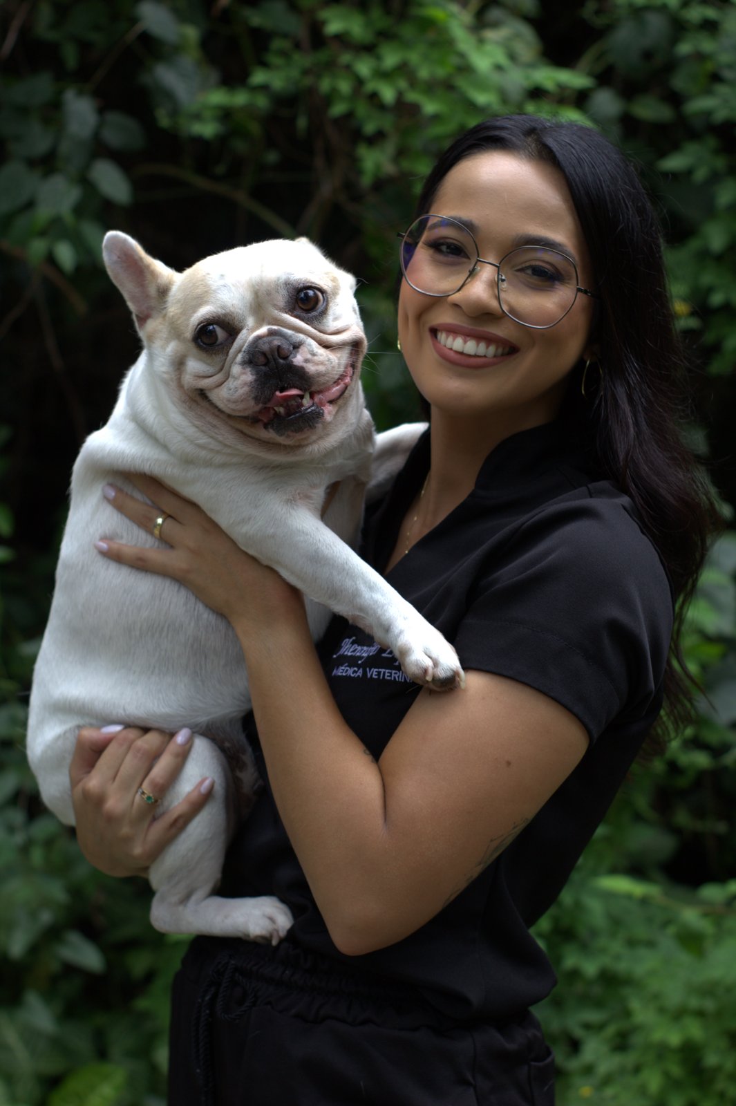 Jhennifer com um bulldog francês, uniforme da Médica do Pet
